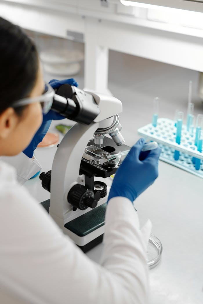 Photo of a Scientist Using a Dropper on a Microscope